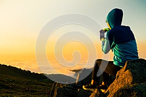 Female persons hands are holding the smartphone and taking a photo of the sunset. Smartphone photography