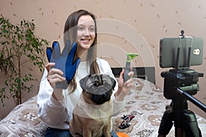Female pet blogger. Woman recording video review of grooming products for dogs on her phone