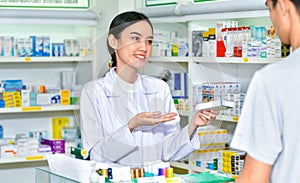 Female pharmacist holding medicine giving advice to customer in pharmacy