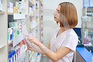 Female pharmacist searching for medicaments from prescription.