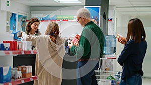 Female pharmacist serving clients with pills and medicaments