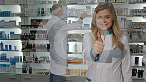 Female pharmacist shows her thumb up at the drugstore