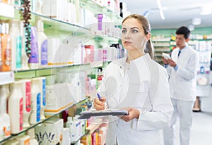 Female pharmacist stocktaking medicines
