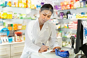 Female pharmacist working in pharmacy, using computer screen