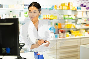 Female pharmacist working in pharmacy, using computer screen