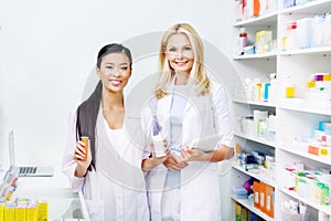 female pharmacists with digital tablet and medication smiling at camera