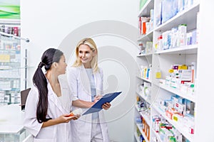 female pharmacists with medication and clipboard working together