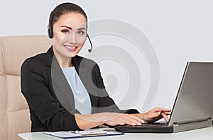 Female phone operator is smiling and and talks on the phone. Helpline answering. Work in the office. Call Center Service