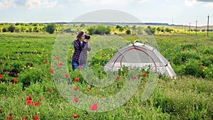 Female photographer on flower field near travel tent