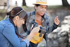 female photographer focusing camera with friend watching