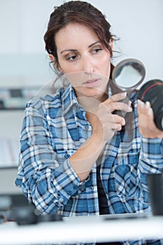 female photographer with magnifier checking lens