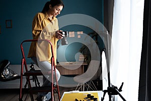 Female photographer setting up camera in home studio. Modern blogger. Content creator. Woman shooting photos.