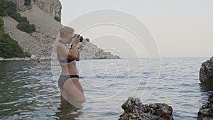 Female photographer standing in sea and giving instructions to model