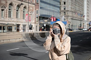 Female photographer taking a candid shot of a busy street with her Nikon FG 20 camera