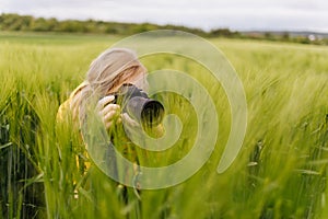 Female photographer taking photos of green wheat field