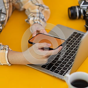 Female photographer working smartphone and laptop on  stylish workspace in home office room