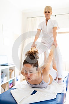 Female physical therapist pulling arms of patient