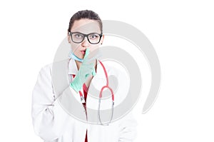 Female physician with eyeglassess doing shush gesture