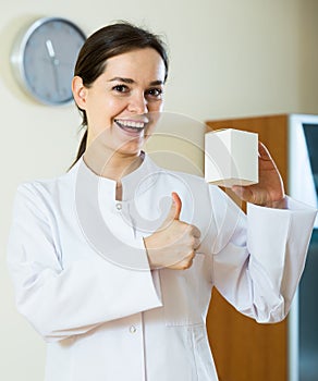 Female physician with stethoscope holding vitamin tablets in pac