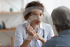 Female physician talking to senior patient at visit in hospital