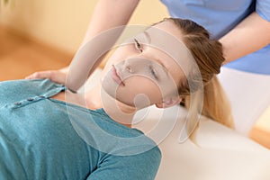 Female physiotherapist or a chiropractor adjusting patients neck. Physiotherapy, rehabilitation concept. Side view cropped shot.