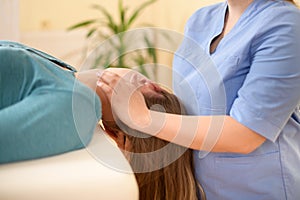 Female physiotherapist or a chiropractor adjusting patients neck. Physiotherapy, rehabilitation concept. Side view cropped shot.