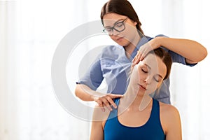 Female physiotherapist or a chiropractor adjusting patients neck. Physiotherapy, rehabilitation concept. White background.