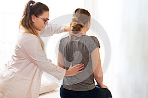 Female physiotherapist or a chiropractor examining patients back. Physiotherapy, rehabilitation concept. photo