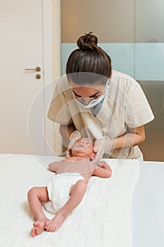 Female physiotherapist doing a positional plagiocephaly correction on a newborn baby in a therapy center.