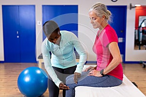 Female physiotherapist examining active senior woman leg in sports center