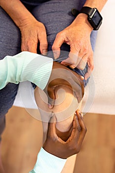 Female physiotherapist giving leg massage to active senior woman in sports center