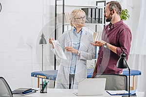 female physiotherapist showing human body picture to patient