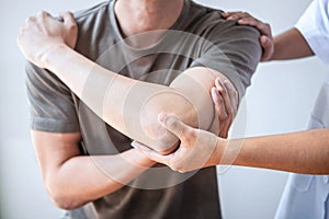 Female Physiotherapist working examining treating injured arm of athlete male patient, stretching and exercise, Doing the