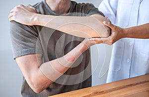 Female Physiotherapist working examining treating injured arm of athlete male patient, stretching and exercise, Doing the