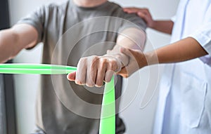 Female Physiotherapist working examining treating injured arm of athlete male patient, stretching and exercise, Doing the