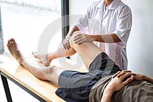 Female Physiotherapist working examining treating injured leg of male patient, Doing exercises the Rehabilitation therapy pain his