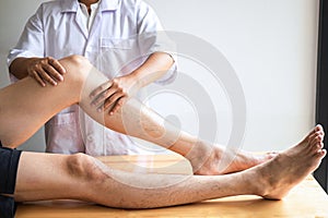 Female Physiotherapist working examining treating injured leg of male patient, Doing exercises the Rehabilitation therapy pain his