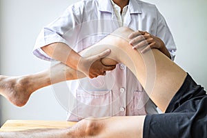 Female Physiotherapist working examining treating injured leg of male patient, Doing exercises the Rehabilitation therapy pain his