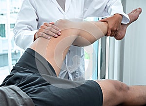 Female Physiotherapist working examining treating injured leg of patient, Doing exercises the Rehabilitation therapy pain his in