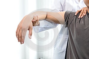 Female physiotherapists provide assistance to male patients with elbow injuries to examine patients in rehabilitation centers.