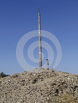 Female pilgrim at the Cruz de Hierro Iron Cross on the Camino de Santiago, Spain.