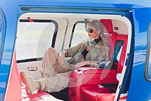 Female pilot in cockpit of helicopter before take off. Young woman helicopter pilot.