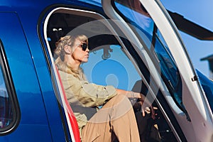 Female pilot in cockpit of helicopter before take off. Young woman helicopter pilot.