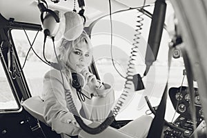 Female pilot in cockpit of helicopter before take off. Young woman helicopter pilot.