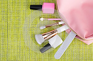 Female pink cosmetic bag on a green background with makeup items