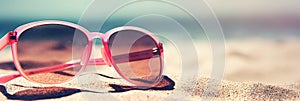 Female pink sunglasses on sand beach. Summer vacation relax concept background. Created with generative Ai