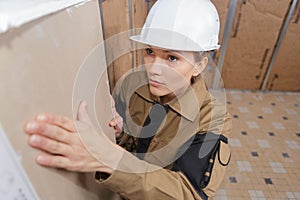 Female plasterer installing material on wall