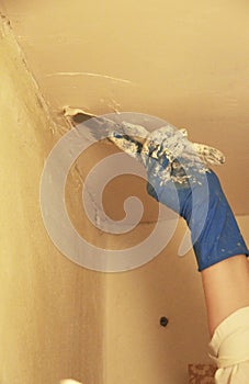 Female plasterer painter repairing a ceiling indoor