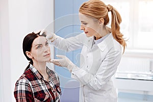 Female plastic surgeon looking at her patients face