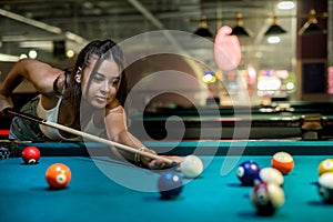female player playing pool and aiming the billiard ball with cue